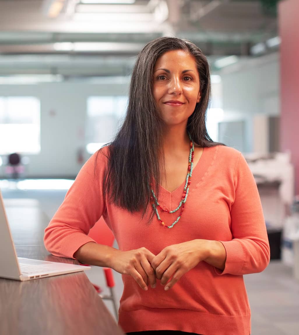 Woman standing wearing pink sweater.